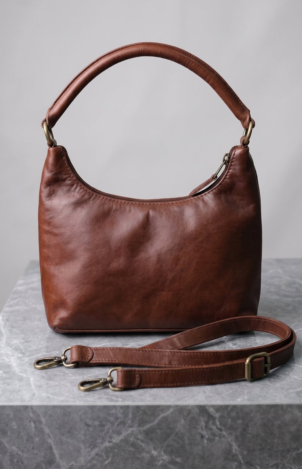 Brut & Beau brown genuine leather hobo handbag displayed on white background