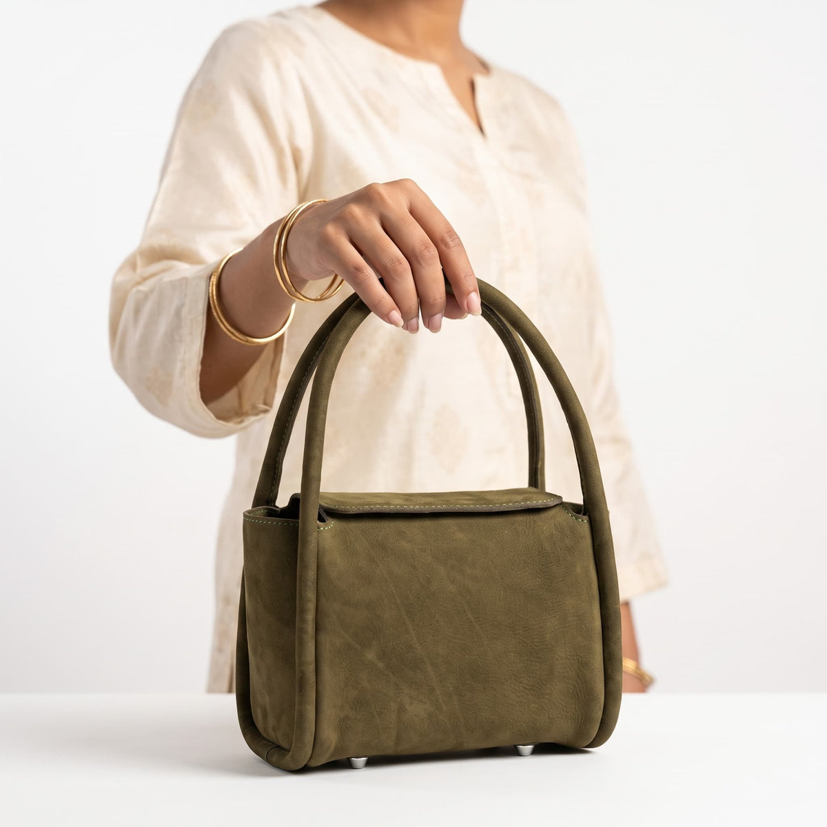 Woman holding olive green leather handbag by its top handles