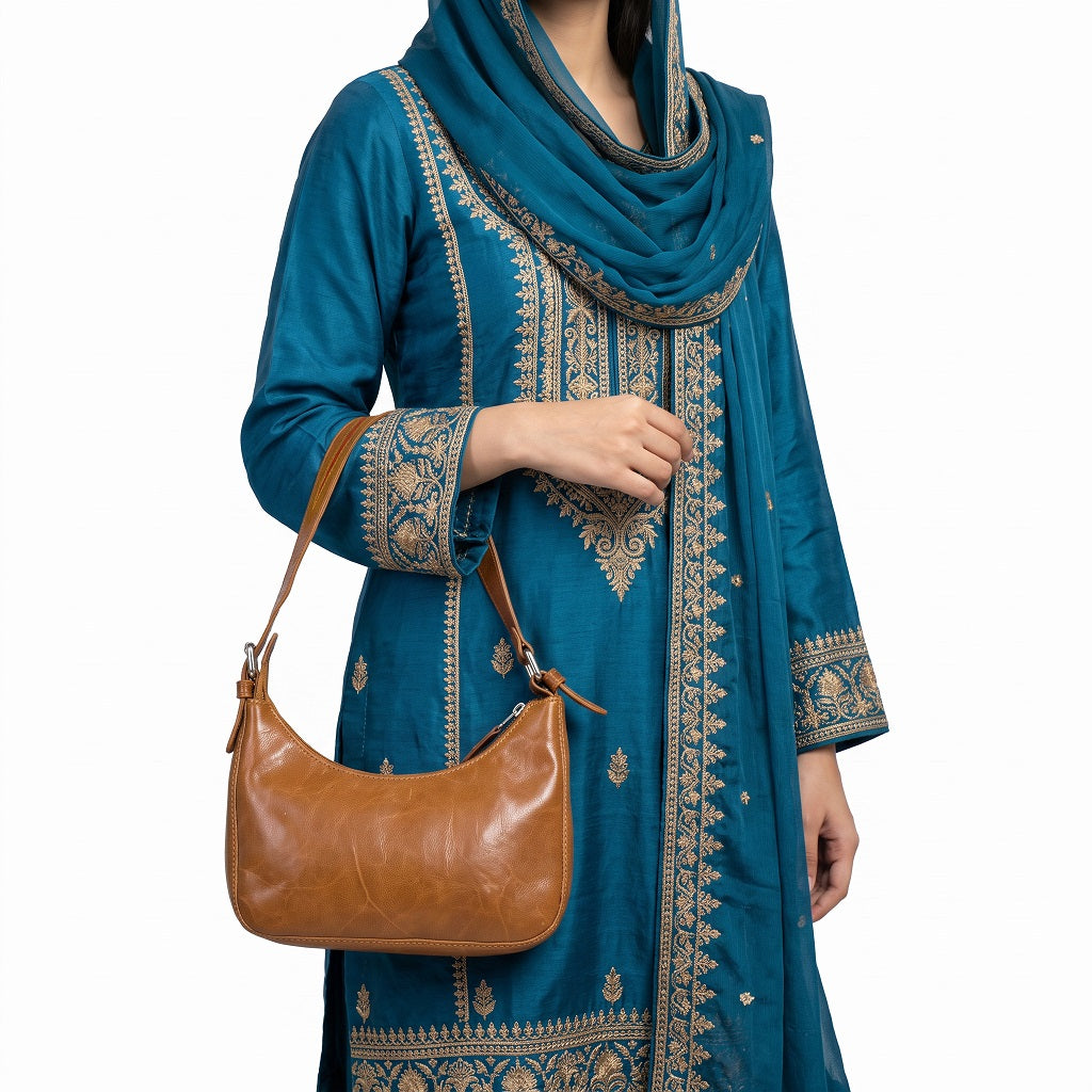 Woman wearing and carrying a classic tan leather shoulder bag outdoors / lifestyle view